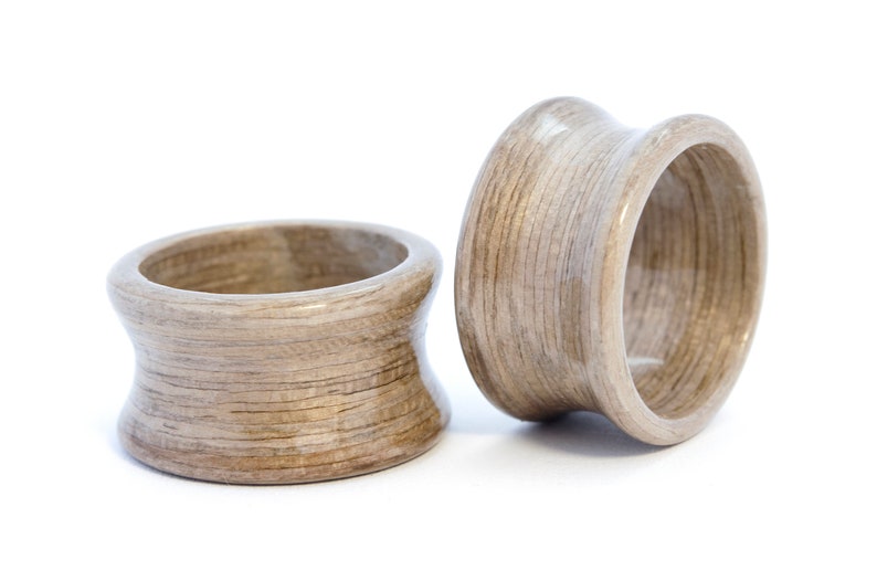 May include: Two wooden rings with a light brown finish. The rings are made of thin layers of wood that are glued together. The rings are smooth and polished.