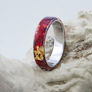 Puede incluir: Un anillo rojo y dorado con una banda plateada. El anillo est&aacute; hecho de resina y presenta escamas de oro reales.