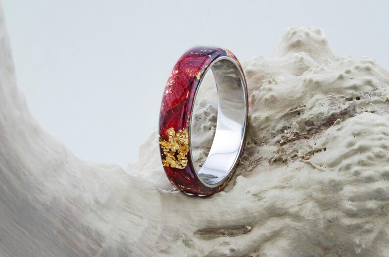 Puede incluir: Un anillo rojo y dorado con una banda plateada. El anillo est&aacute; hecho de resina y presenta escamas de oro reales.