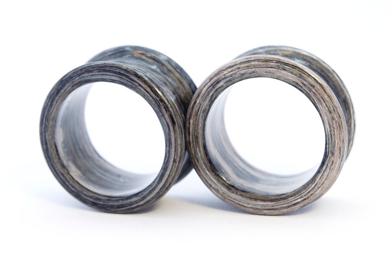 May include: A pair of black and grey wooden ear gauges. The gauges are round and have a smooth, polished finish.