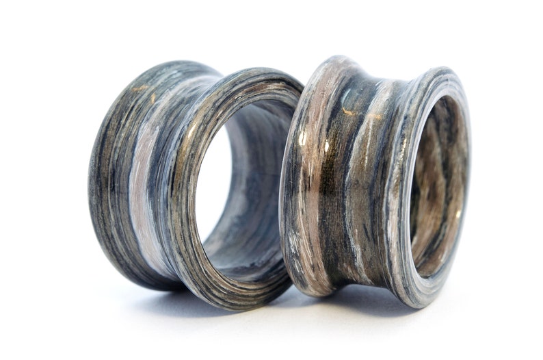 May include: Two wooden ear gauges with a layered, striped pattern in shades of gray, brown, and white. The gauges have a smooth, polished finish.