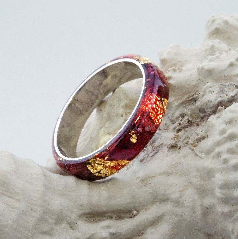 Puede incluir: Un anillo rojo y dorado con una banda plateada. El anillo est&aacute; hecho de resina y tiene un aspecto marmoleado &uacute;nico.