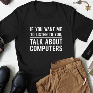 May include: Black t-shirt with white text that reads "If you want me to listen to you, talk about computers."