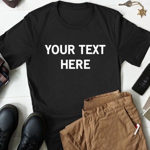 May include: A black t-shirt with the text "YOUR TEXT HERE" printed in white on the front.