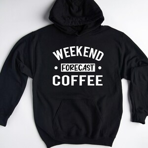 May include: Black hooded sweatshirt with a front pocket and white text that reads "WEEKEND FORECAST COFFEE". The sweatshirt has a drawstring hood and long sleeves. The text is in a bold, sans-serif font.