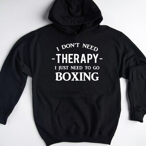 May include: Black hooded sweatshirt with white text that reads "I don't need -therapy- I just need to go BOXING".