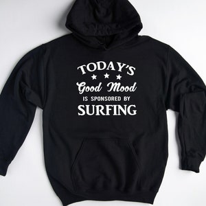 May include: Black hooded sweatshirt with white text that reads "TODAY'S Good Mood IS SPONSORED BY SURFING" with three stars above the word "Good".