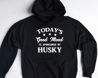 May include: Black hooded sweatshirt with white text that reads "TODAY'S Good Mood IS SPONSORED BY HUSKY" with three stars above the word "Good".