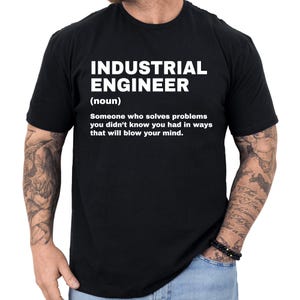 May include: Black t-shirt with the text "INDUSTRIAL ENGINEER" in white, followed by a definition. The definition reads: "Someone who solves problems you didn't know you had in ways that will blow your mind."