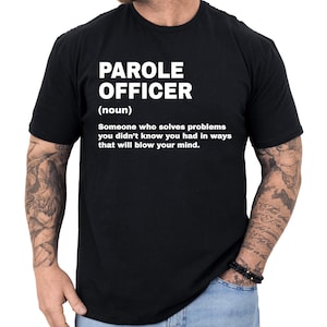 May include: Black t-shirt with the words "PAROLE OFFICER" in large white capital letters. Below the title is the word "(noun)" and a definition: "Someone who solves problems you didn't know you had in ways that will blow your mind."