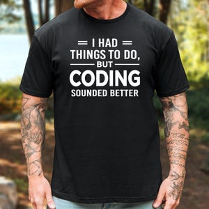 May include: A black short-sleeved t-shirt featuring white text that reads I HAD THINGS TO DO, BUT CODING SOUNDED BETTER. The shirt has a crew neckline and a standard fit, with the graphic centered on the chest in a bold, sans-serif typeface.
