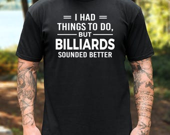 May include: A black short-sleeved t-shirt featuring white text that reads: I HAD THINGS TO DO, BUT BILLIARDS SOUNDED BETTER. The shirt has a crew neckline and a standard fit, with the graphic centered on the chest in a bold, sans-serif font.