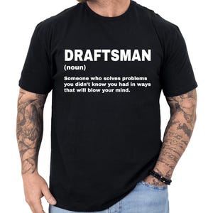 May include: Black t-shirt with the word "DRAFTSMAN" in white, followed by a definition. The definition reads: "Someone who solves problems you didn't know you had in ways that will blow your mind."