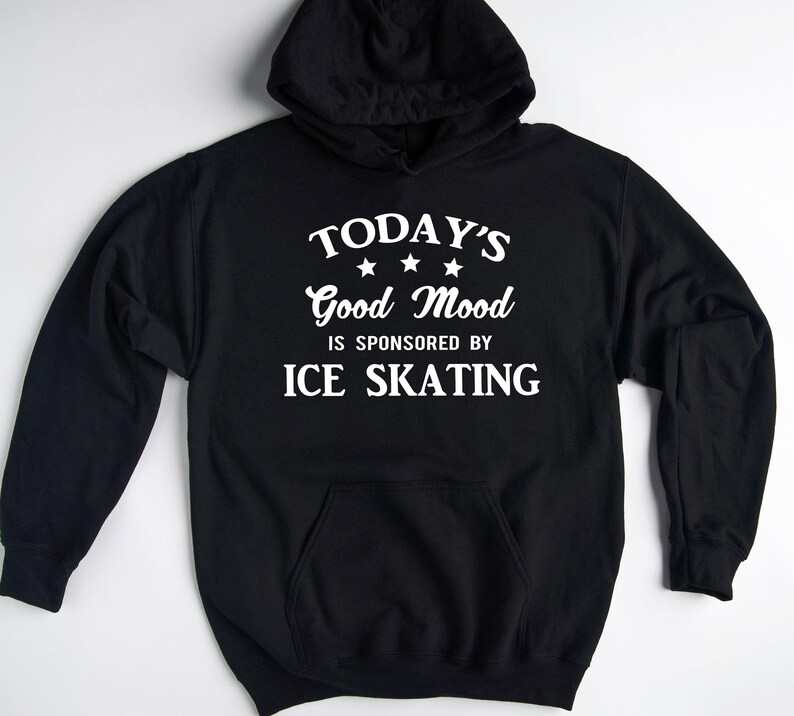 Pu&ograve; includere: Felpa con cappuccio nera con testo bianco che recita "TODAY'S Good Mood IS SPONSORED BY ICE SKATING" con tre stelle bianche sopra la parola "Good".