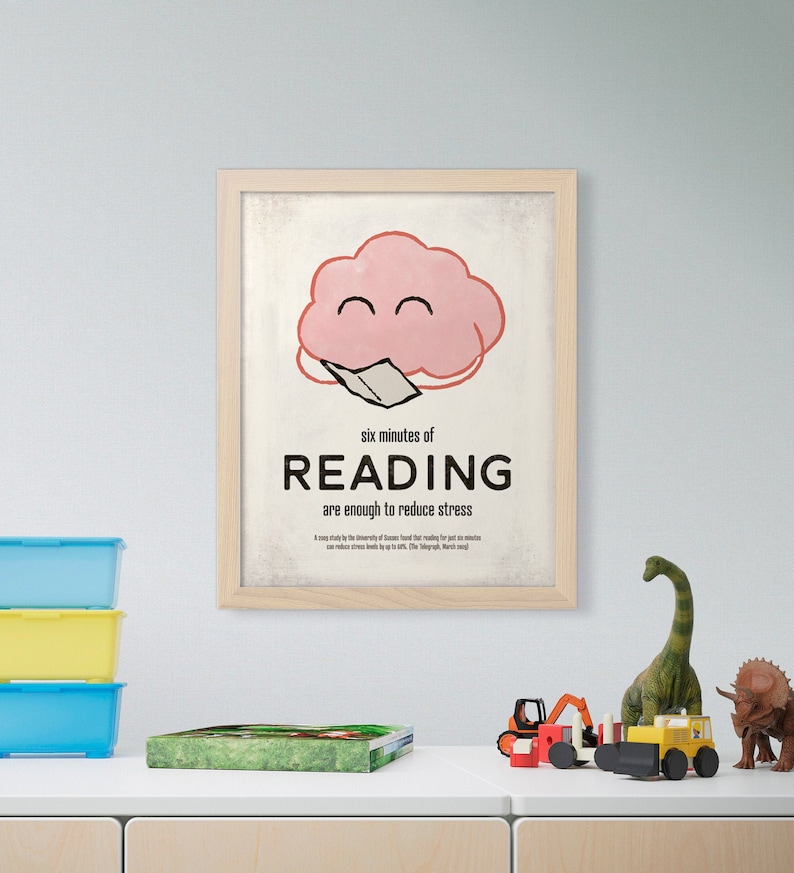 K&ouml;nnte beinhalten: Ein gerahmter Druck mit einem hellen Holzrahmen. Der Druck zeigt eine rosa Wolkenfigur, die ein Buch liest, mit dem Text "six minutes of READING are enough to reduce stress". Spielzeug befindet sich auf dem Regal darunter.