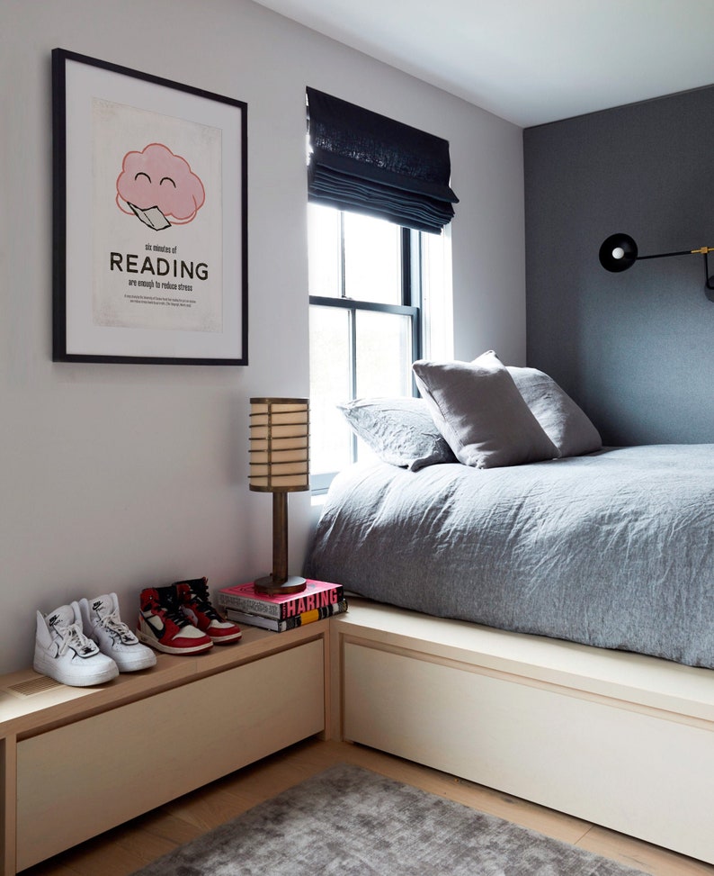 K&ouml;nnte beinhalten: Ein Schlafzimmer mit einem gerahmten Poster mit der Aufschrift "six minutes of READING are enough to reduce stress". Ein Paar wei&szlig;e und rote Turnschuhe stehen auf einem hellen Holzschrank. Eine Lampe und B&uuml;cher befinden sich ebenfalls auf dem Schrank. Das Bett hat graue Bettw&auml;sche.
