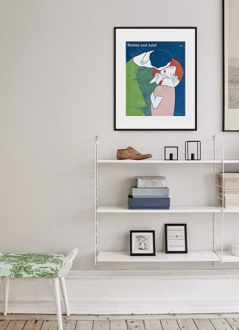 May include: A framed poster with a minimalist illustration of a couple embracing. The poster is titled "Romeo and Juliet" and is set against a blue background with white stars.