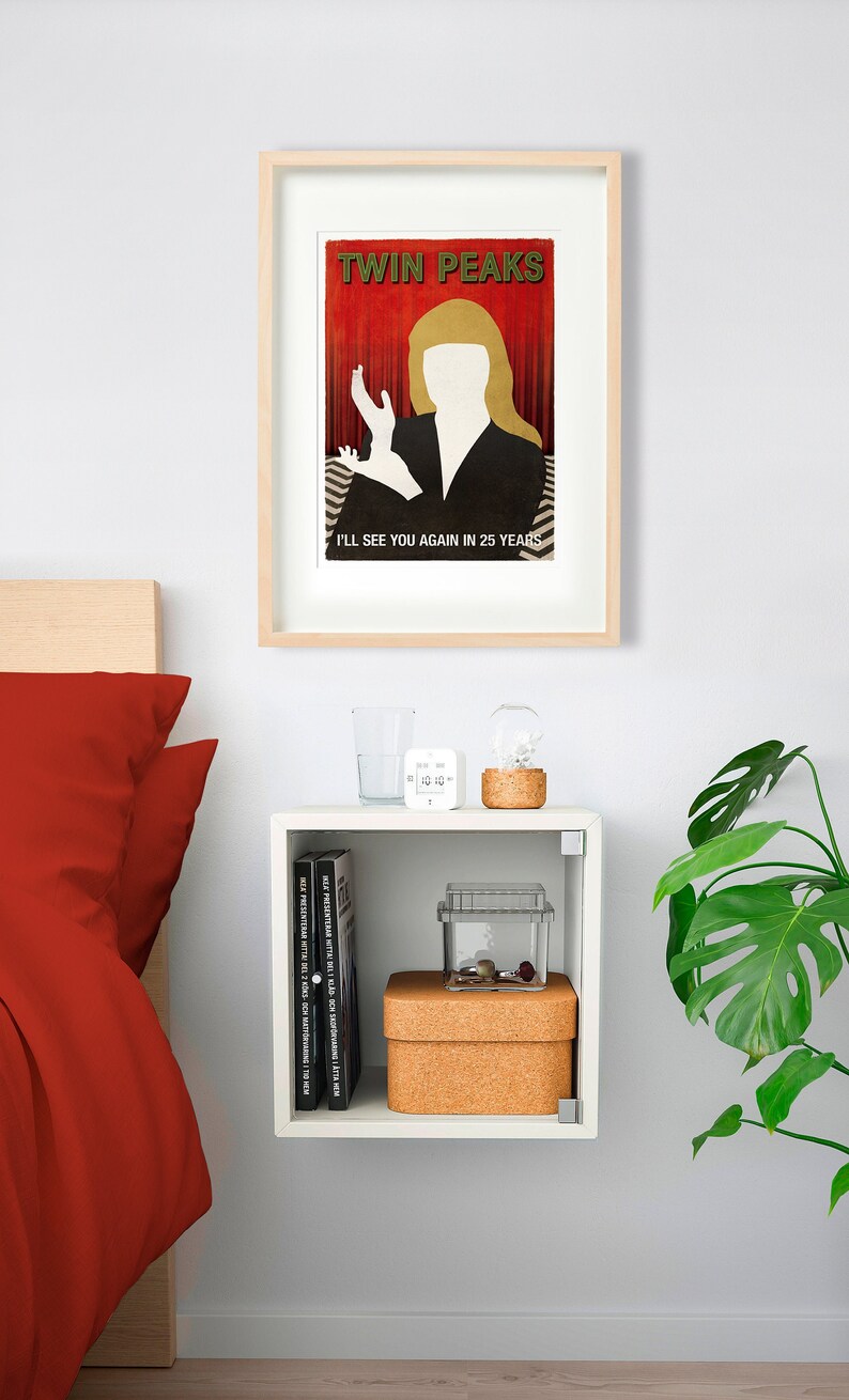 Op de afbeelding: Een ingelijste poster met een rode achtergrond en een wit silhouet van een vrouw met blond haar. De poster zegt "Twin Peaks" en "Ik zie je over 25 jaar weer".