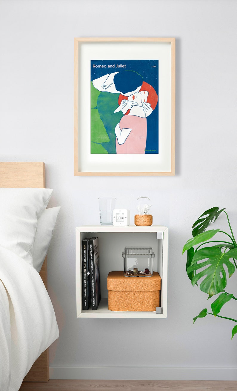 May include: A white nightstand with a glass shelf and a cork-topped box. The nightstand is decorated with a framed poster of a couple embracing, a glass of water, a white digital clock, and a glass terrarium with a small plant. A green potted plant is on the right side of the image.