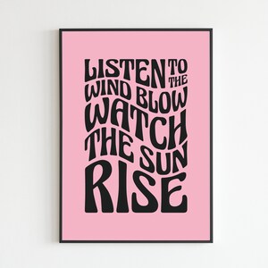 May include: Pink poster with black text that reads "Listen to the wind blow watch the sun rise".