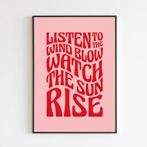 May include: A pink poster with black frame featuring red text that reads "Listen to the wind blow watch the sun rise".