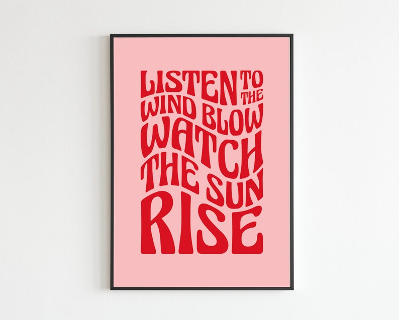 May include: A pink poster with black frame featuring red text that reads "Listen to the wind blow watch the sun rise".
