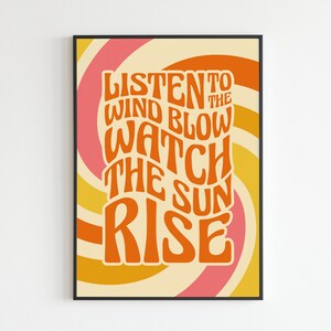 May include: A retro-style poster with a swirling orange, yellow, and pink background. The text reads "Listen to the wind blow watch the sun rise" in a bold, orange font.