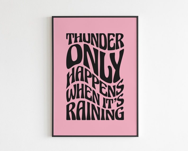 May include: A framed art print with a pink background and black text. The text reads "THUNDER ONLY HAPPENS WHEN IT'S RAINING" in a wavy, stylized font. The frame is black.
