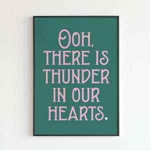 May include: A teal green poster with a black frame featuring pink text that reads "Ooh, there is thunder in our hearts." with a small pink heart at the end.