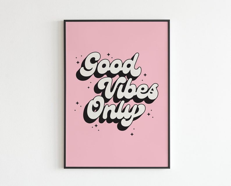 May include: A pink poster with black and white text that reads "Good Vibes Only" with a retro font style. The poster has a black frame.