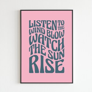 May include: A pink poster with a dark blue text overlay that reads "Listen to the wind blow watch the sun rise".