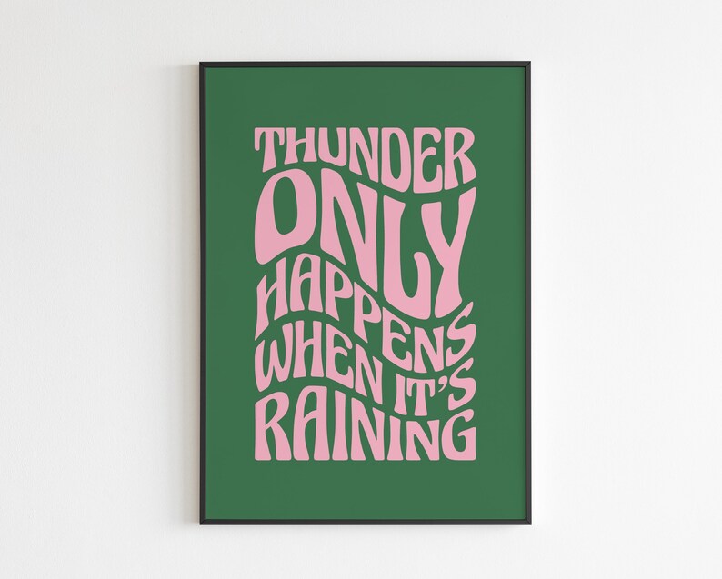 May include: A framed print with a green backdrop and pink text. The text reads "THUNDER ONLY HAPPENS WHEN IT'S RAINING" in a retro, wavy font. The frame is black.