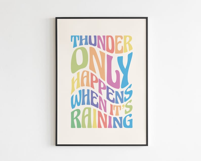 May include: A framed art print featuring the quote "THUNDER ONLY HAPPENS WHEN IT'S RAINING" in a vibrant, wavy font. The text uses a palette of blues, greens, yellows, oranges, and purples on a cream backdrop, enclosed in a black frame.