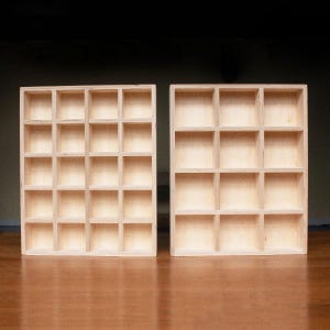 May include: Two wooden display shelves with 16 square compartments each. The shelves are made of light-colored wood and are empty.