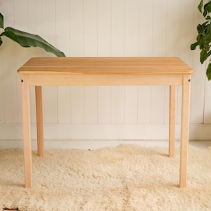 May include: A handmade, wooden serving tray with a natural finish. The tray features a rectangular shape with raised edges and two cut-out handles. The wood grain is visible, showcasing the tray's rustic charm. Dimensions are approximately 12 inches long and 8 inches wide.