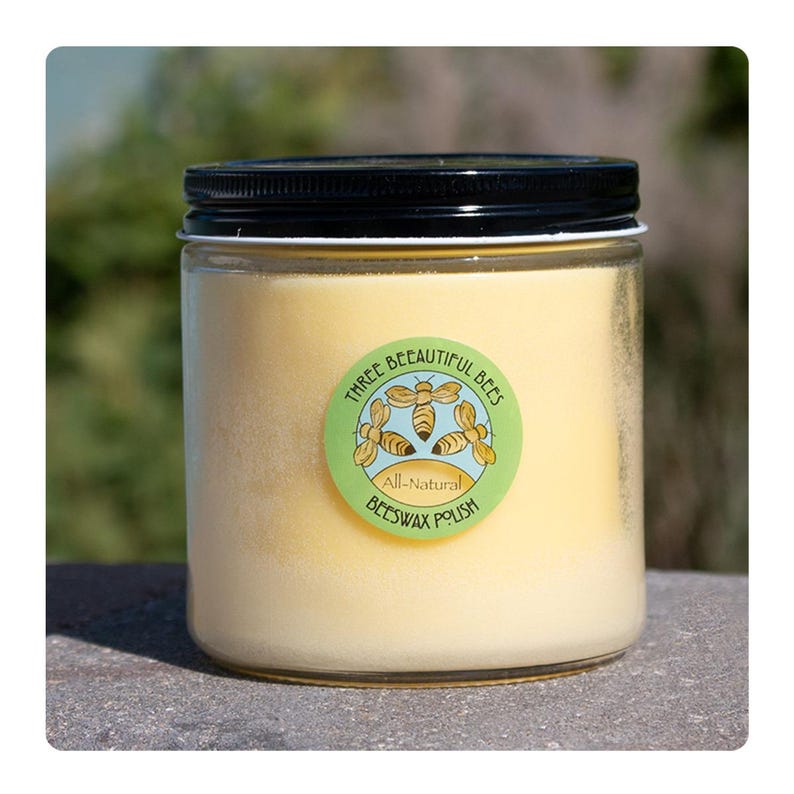 Może przedstawiać: Szklany słoik z ż&oacute;łtym woskiem pszczelim do polerowania z zielono-białą etykietą z napisem "Three Beautiful Bees All-Natural Beeswax Polish" i rysunkiem trzech pszcz&oacute;ł.