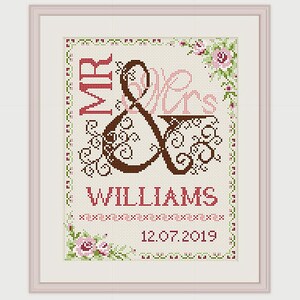 May include: Cross-stitch pattern with a brown and black ampersand symbol with floral embellishments. The text "MR & MRS WILLIAMS" and the date "12.07.2019" are stitched in red.