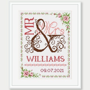 May include: Cross-stitch pattern with a brown and pink "Mr. & Mrs." design with a floral border and the text "WILLIAMS 09.07.2021".