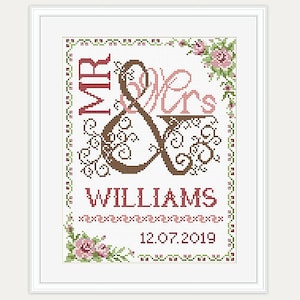 May include: Cross-stitch embroidery design featuring a stylized ampersand with the words "Mr & Mrs Williams" and the date "12.07.2019". The design is framed with a floral border.