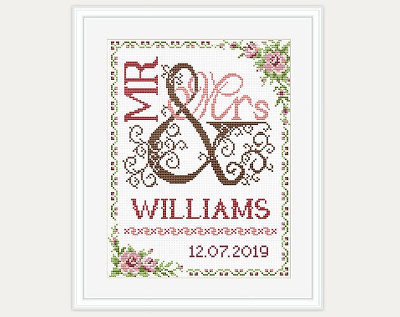 May include: Cross-stitch embroidery design featuring a stylized ampersand with the words "Mr & Mrs Williams" and the date "12.07.2019". The design is framed with a floral border.
