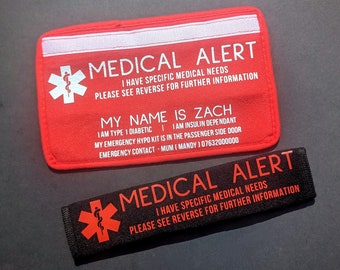 May include: Two red and black medical alert cards with white text. The top card says "MEDICAL ALERT" and "I HAVE SPECIFIC MEDICAL NEEDS PLEASE SEE REVERSE FOR FURTHER INFORMATION". The bottom card says "MY NAME IS ZACH I AM TYPE 1 DIABETIC I AM INSULIN DEPENDANT MY EMERGENCY HYPO KIT IS IN THE PASSENGER SIDE DOOR EMERGENCY CONTACT - MUM (MANDY) 07632000000".