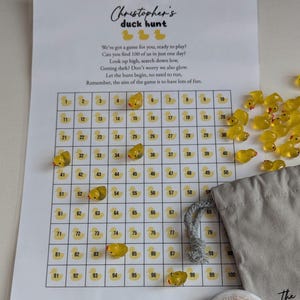 May include: A duck hunt game set with a numbered grid, yellow duck figurines, a drawstring bag, and a champion's badge. The printed sheet includes instructions and the text "Christopher's duck hunt". The game is designed for fun.