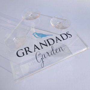 May include: A clear acrylic bird feeder with suction cups. The feeder has a blue bird graphic and the text "GRANDADS Garden".