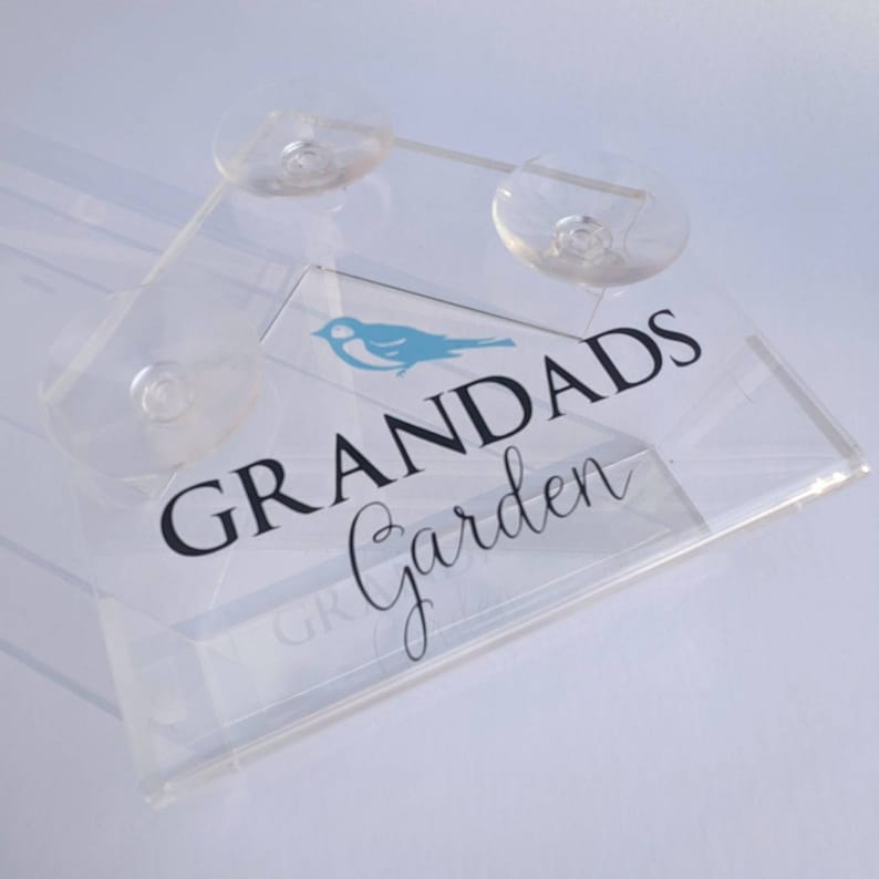 May include: A clear acrylic bird feeder with suction cups. The feeder has a blue bird graphic and the text "GRANDADS Garden".