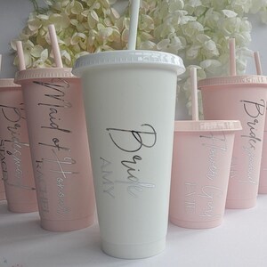 May include: Set of pink and white reusable cups with straws. The cups are personalised with the text "Bride", "Maid of Honour", "Bridesmaid", "Flower Girl", and "Bride Squad".