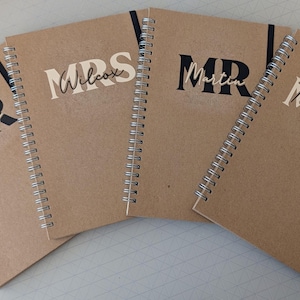 May include: Four brown spiral notebooks with black and white text. The notebooks are labelled "MR Davies", "MRS Wilcox", "MR Martin", and "MISS Thompson".