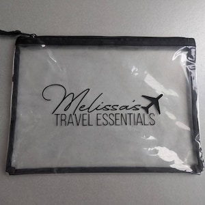 May include: Clear plastic travel pouch with a black zipper and black trim. The pouch has the text "Melissa's Travel Essentials" printed on it.