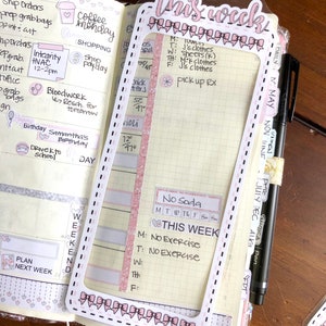 Op de afbeelding: Een roze en witte wekelijkse planner sticker met de tekst "This week" in roze cursief schrift. De sticker heeft een decoratieve rand van roze strikken en een wit frame. De sticker is geplaatst op een wekelijkse planner pagina met een rasterpatroon. De planner pagina heeft handgeschreven notities voor de week, waaronder "No Soda" en "No Exercise".