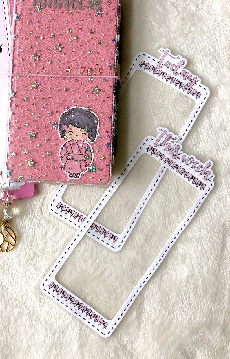 Op de afbeelding: Twee transparante planner stickers van plastic met roze strikken rond de randen. De bovenste sticker zegt "Vandaag" en de onderste sticker zegt "Deze week".