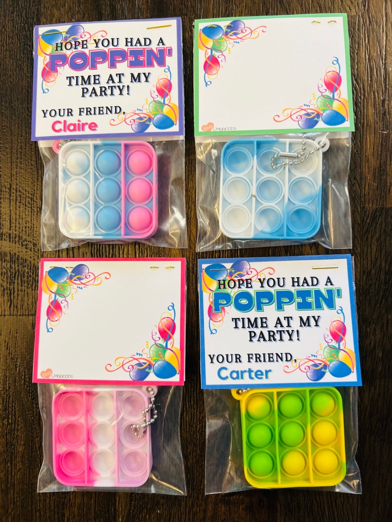 May include: Four party favour bags with colourful pop-it toys and a tag that says "Hope you had a poppin' time at my party!" with a name at the bottom. The bags are clear plastic and the tags are decorated with balloons.